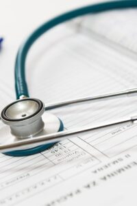 A stethoscope and pen resting on a medical report in a healthcare setting.