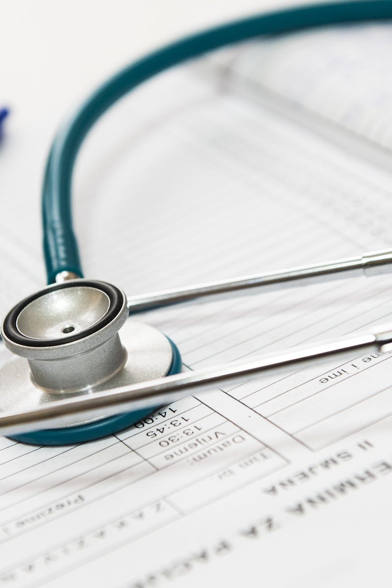 A stethoscope and pen resting on a medical report in a healthcare setting.