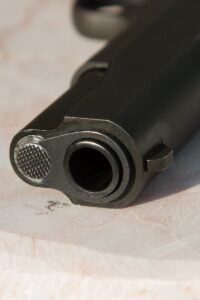 Detailed close-up of a gun barrel resting on a marble surface, highlighting the metal texture.