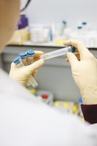 Scientist examining test tubes in a laboratory setting, wearing protective gloves.