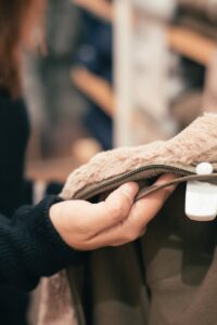 Close-up of a woman examining a coat in a clothing store, focused on texture and design.