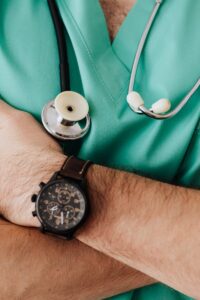 Close-up of a healthcare professional with arms crossed wearing medical scrubs and stethoscope.