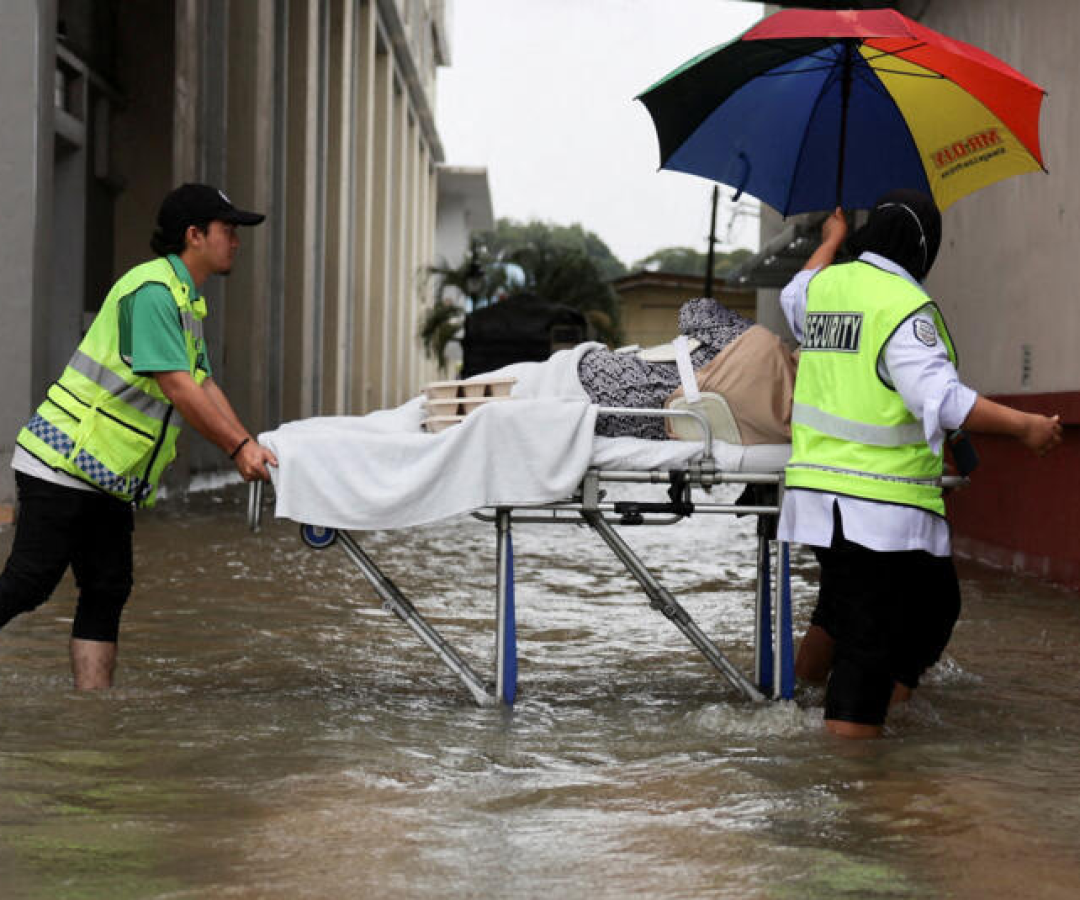 Profissionais de resgate transportam um paciente em maca após as fortes chuvas no norte da Malásia