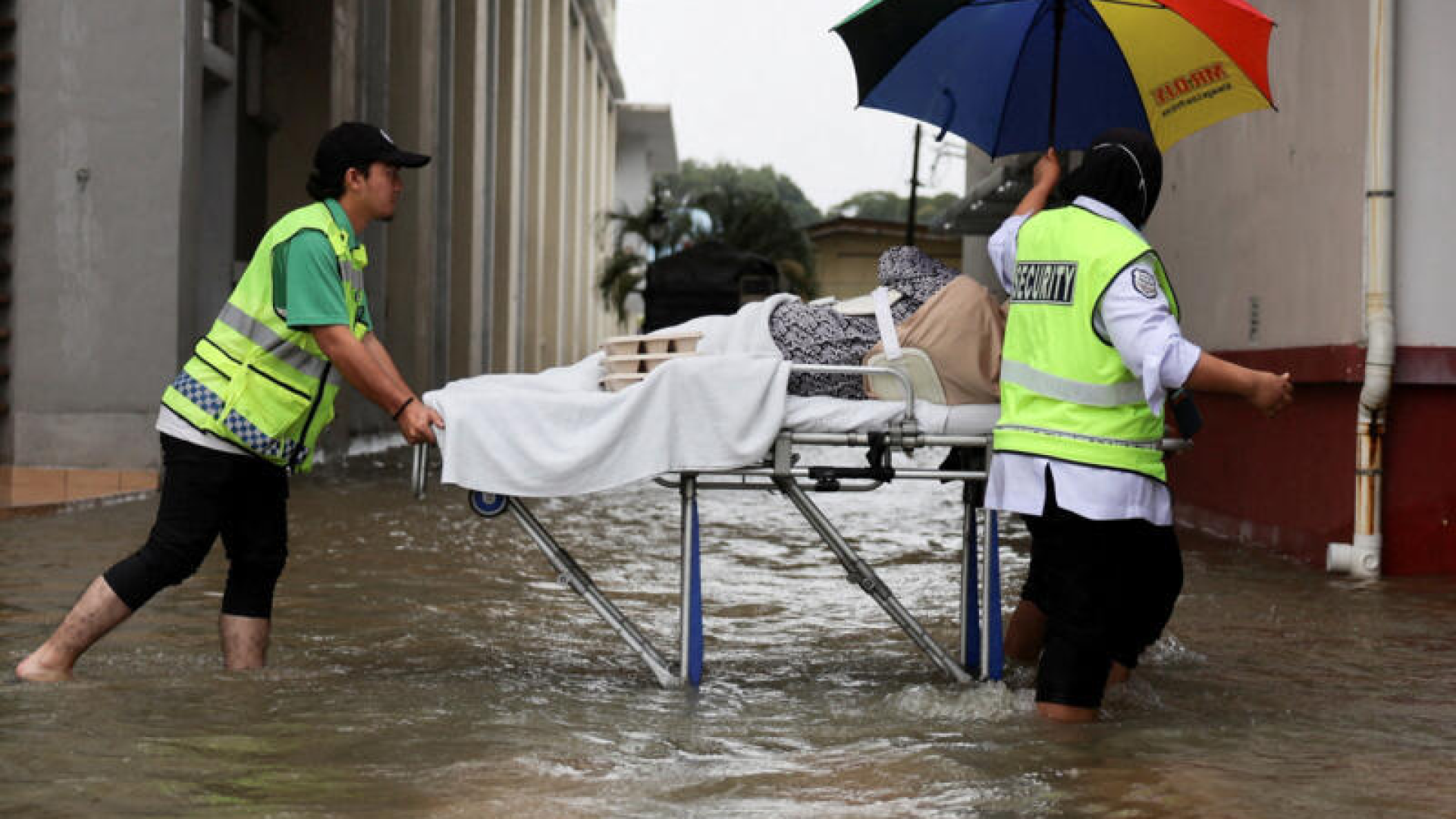 Profissionais de resgate transportam um paciente em maca após as fortes chuvas no norte da Malásia